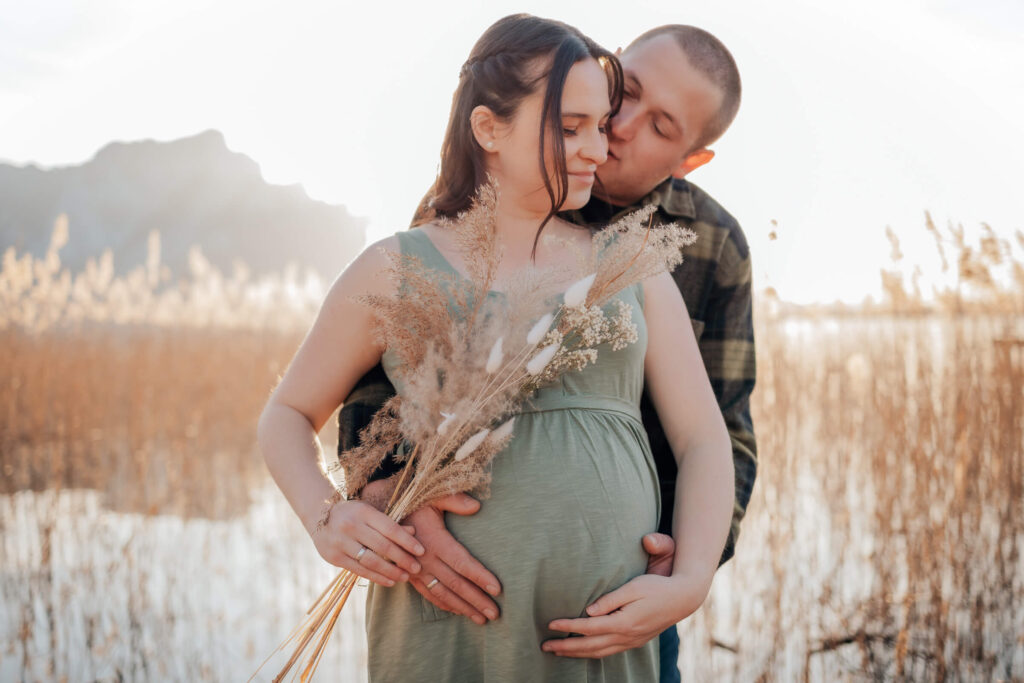 Babybauchshooting am Mondsee. Paar küsst sich.