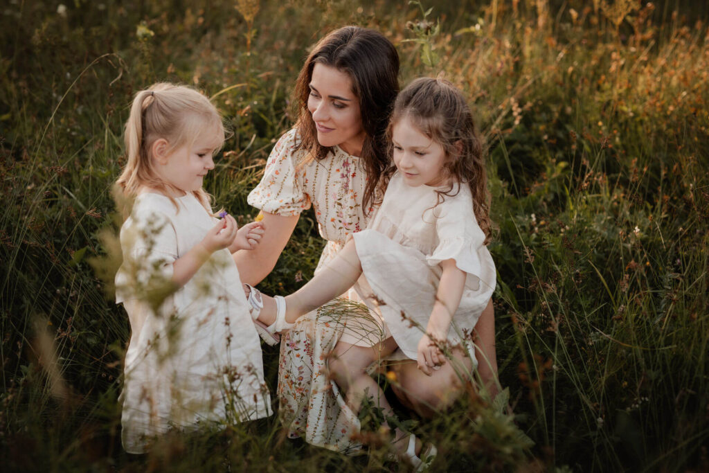 Einen Mama mit ihren zwei Mädchen bei einem Familienfotoshooting auf einer Wiese am Mondsee im Salzkammergut