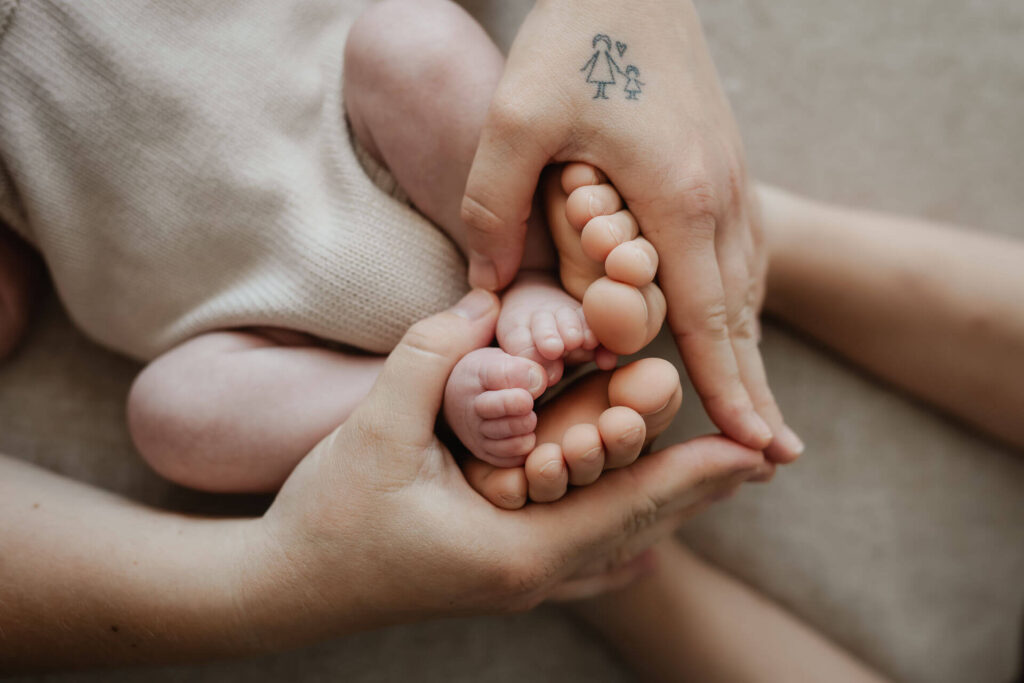 Eine Mutter formt mit ihren Händen ein Herz um die kleinen Zehen ihrer beiden kleinen Kinder bei einem Familienfotoshooting am Mondsee.